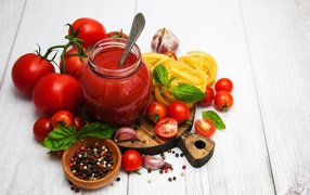 Ketchup on a table with tomatoes, spices and pasta