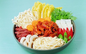 Meat in a plate with vegetables, mushrooms and noodles on a blue background