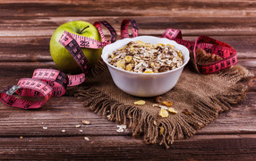 Muesli on a table with a green apple and a centimeter