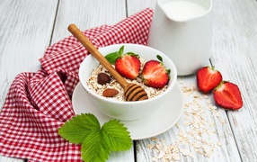 Oatmeal on a table with milk and strawberries