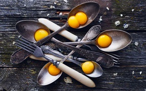 Old spoons with yolks on a wooden table