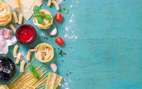 Pasta on a blue table with tomatoes and garlic