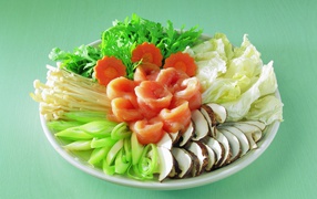 Тарелка с овощами и красной рыбой на зеленом фоне