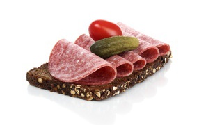 Sandwich with black bread, sausage, salted cucumber and tomato on white background