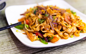 Spicy noodles with vegetables on a white plate