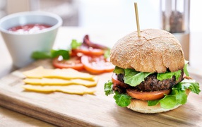 Аппетитный гамбургер на доске с сыром и помидорами