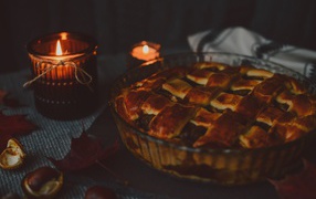 Tasty meat pie on a table with candles