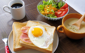 Toast with fried eggs and bacon on the table with salad, coffee and soup
