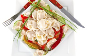 White plate with dumplings, red pepper and cucumbers