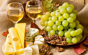 White wine on the table with cheese, grapes and nuts
