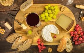 Wine, cheese, grapes and baguette on the table
