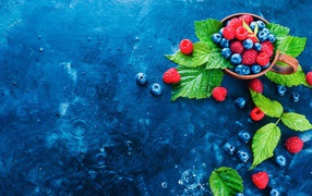 Чашка с ягодами черники и малины на синем столе