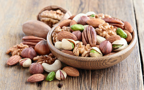 Разные орехи в деревянной тарелке на столе