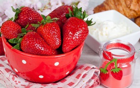 Свежие ягоды клубники в красной миске на столе