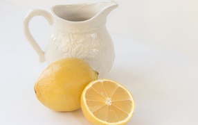 Лимон с белым кувшином на сером фоне