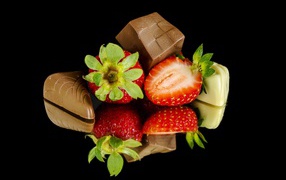 Red fresh strawberry with chocolate candies on a black background