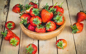 Ripe red strawberries in a wooden bowl on the table