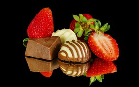 Клубника и шоколадные конфеты на черном фоне