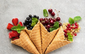 Waffle cones with berries on a gray background