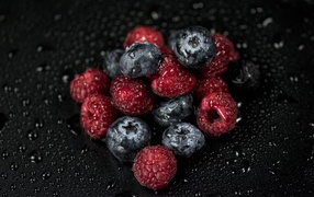 Мокрые ягоды черники и малины на черном фоне