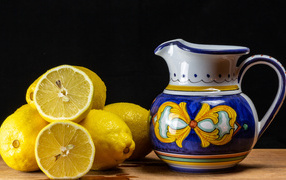 Желтые лимоны на столе с кувшином