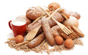 Fresh bread on a white plate with eggs, a cup of milk and oatmeal