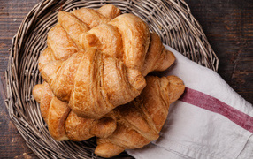 Fresh croissants in a wicker basket with a towel