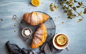 Two fresh croissants on a table with tea