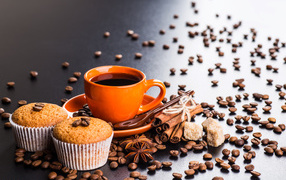 Чашка кофе на столе с кексами, кофейными зернами, корицей и бадьяном