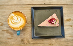 A piece of cake on a black plate with coffee