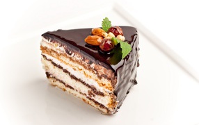 Кусок торта с шоколадом и орехами на белом фоне