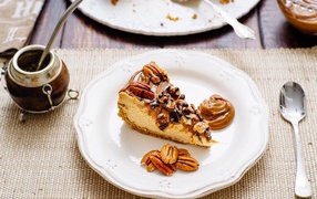 Кусок торта с орехами на белой тарелке на столе с кофе