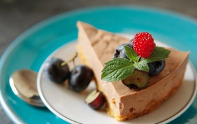 Кусок чизкейка на тарелке с ягодами черники и малиной