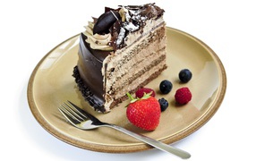 Кусок торта с кремом на тарелке с ягодами и вилкой