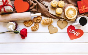 Appetizing sweet pastry on the table with coffee, hearts and gifts