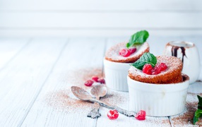 Пирожное с ягодами и сахарной пудрой на столе с ложками