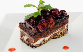 Пирожное с черешней и листиками мяты на сером фоне