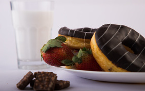 Пончики с шоколадной глазурью на тарелке с клубникой