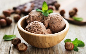 Шоколадное мороженое в деревянной миске на столе с орехами