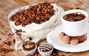 Chocolates on the table with a cup of coffee and a bag of coffee beans