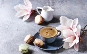 Кофе на столе с макарунами, молоком и цветами 