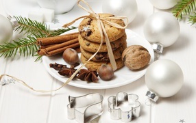 Печенье на тарелке с орехами и корицей на столе с игрушками 