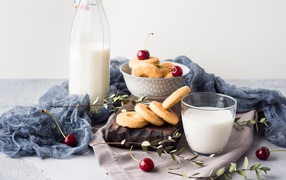 Cookies on a table with milk and cherries