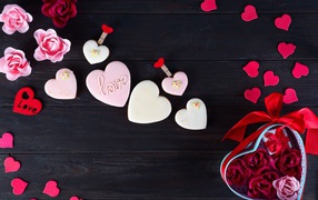 Печенье с глазурью на черной поверхности с сердечками и подарком