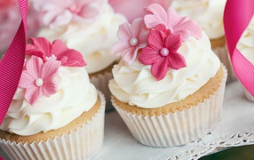 Cupcakes with cream and pink flowers close up