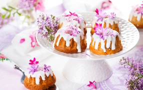 Кексы с глазурью на подносе с цветами сирени 