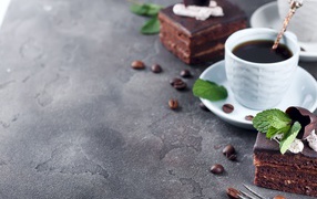 Аппетитное шоколадное пирожное на сером столе с чашкой кофе