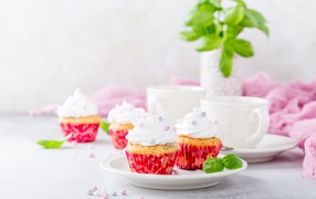 Аппетитные кексы с кремом на столе с чашками