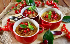 Десерт в красной посуде на столе с вишней и красной смородиной