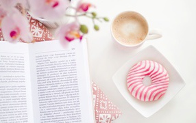 Пончик с чашкой кофе на столе с книгой